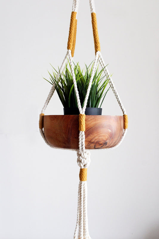 Handmade off-white cotton macrame plant hanger holding a green potted plant against a neutral wall by Freefille