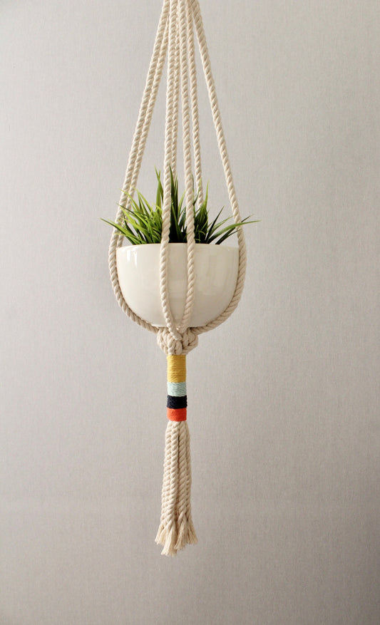 Modern cream macramé plant hanger with colorful navy, orange, mint blue, and yellow wrapped cord details by Freefille