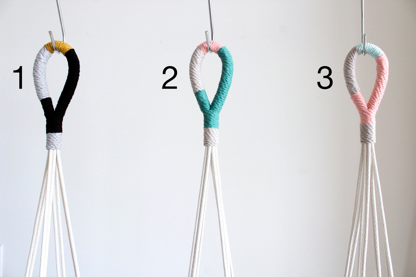 Three macrame wall hanging loops numbered 1, 2, and 3, shown against a plain light background. Each loop is wrapped in different color combinations: black and white with a small yellow accent, teal and pink, and mint green and pink.