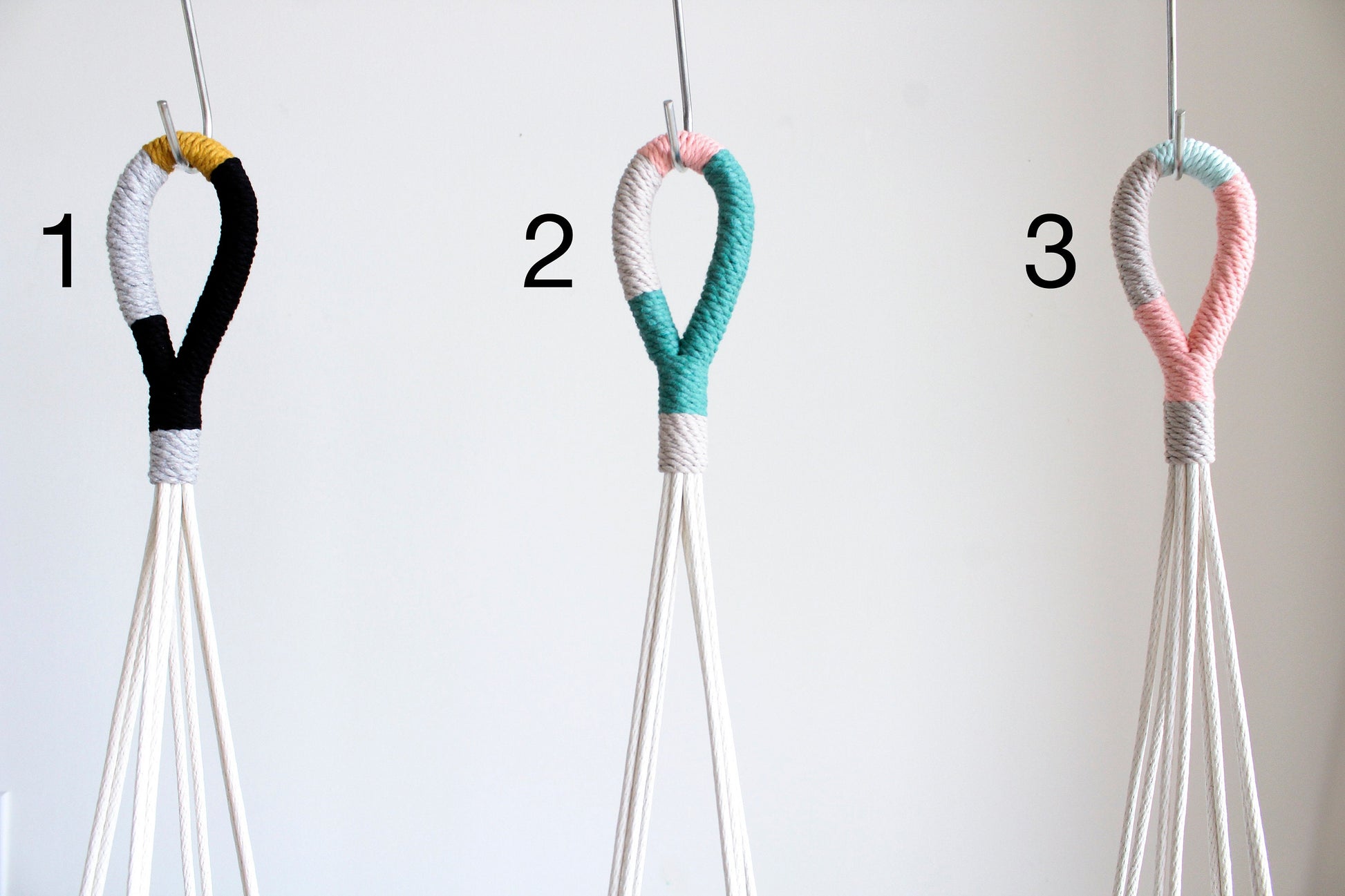 Three macrame wall hanging loops numbered 1, 2, and 3, shown against a plain light background. Each loop is wrapped in different color combinations: black and white with a small yellow accent, teal and pink, and mint green and pink.