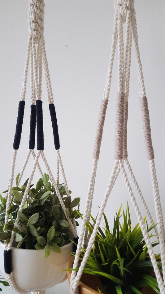 Two macrame plant hangers with plants against a white wall made by Freefille