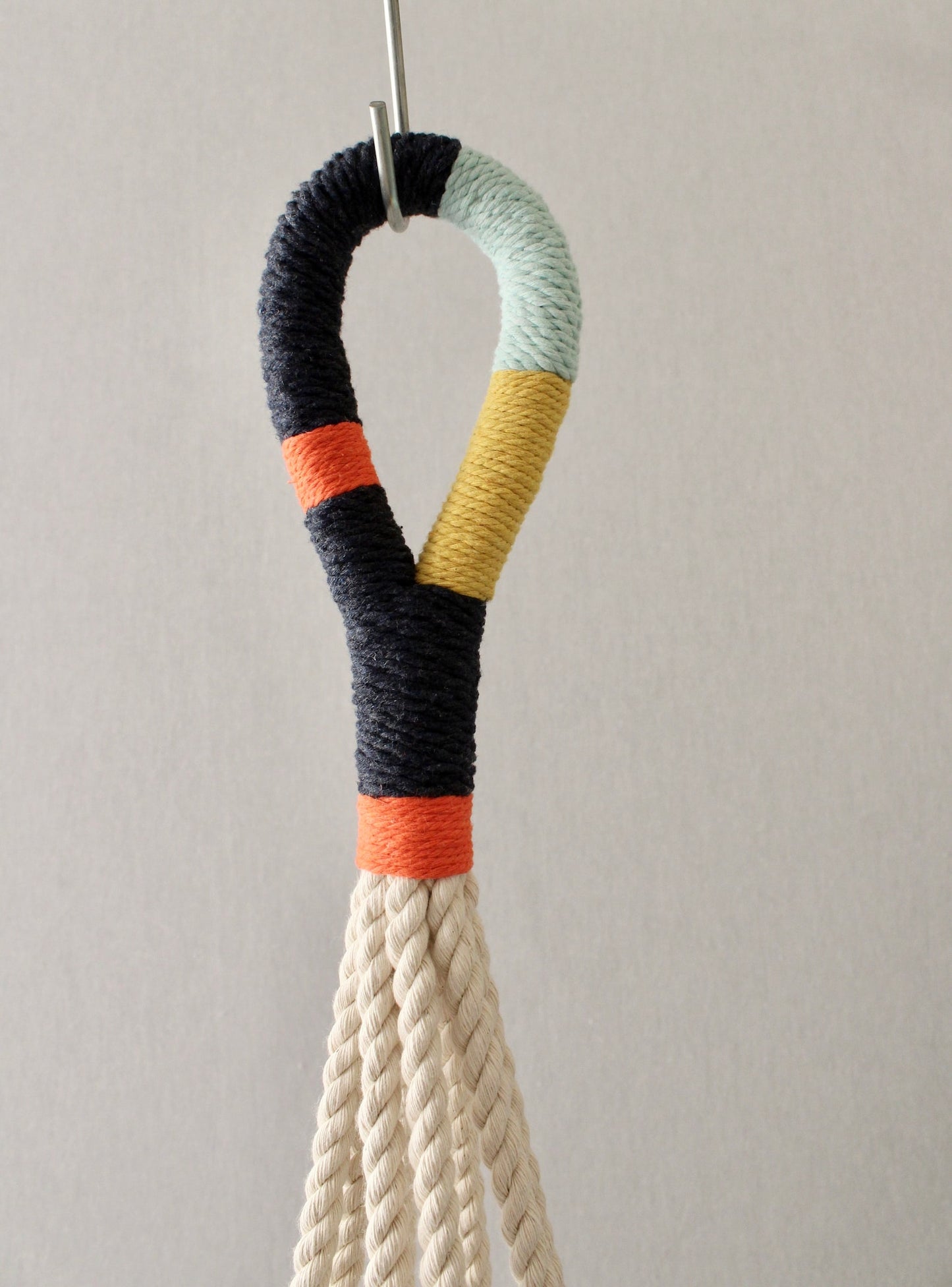 Modern macrame plant hanger with colorful navy, orange, mint blue, and yellow wrapped cord details by Freefille.