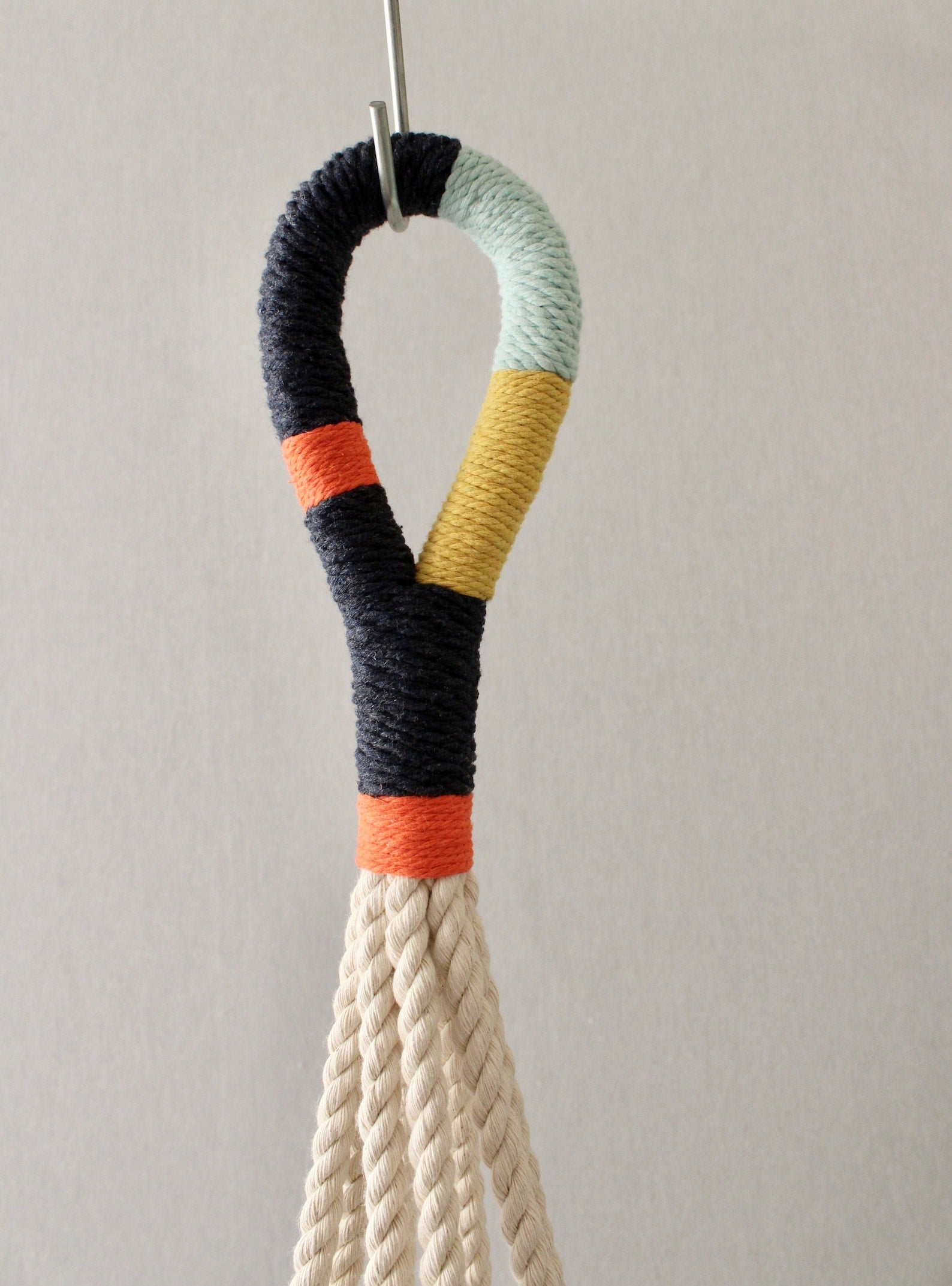 Modern macrame plant hanger with colorful navy, orange, mint blue, and yellow wrapped cord details by Freefille.