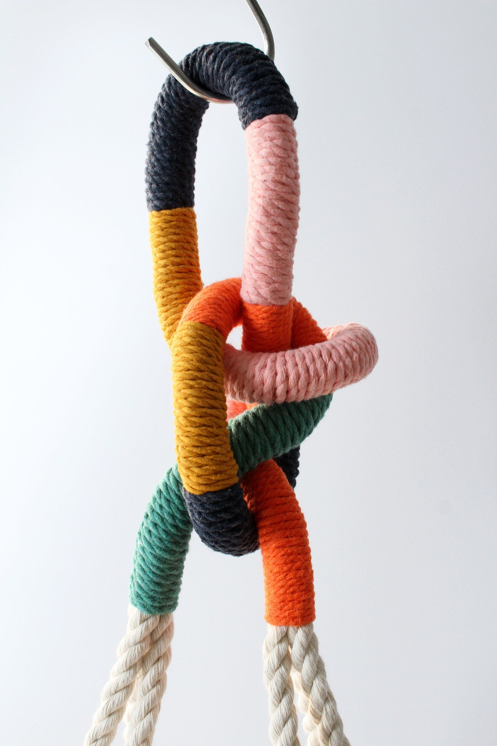 Colorful knotted rope hanging against a white background made by Freefille