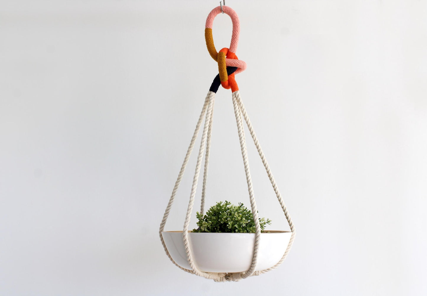 Tassel-free macrame plant hanger with mustard yellow, pink, orange wrapped top loop knot holding a white ceramic bowl by Freefille