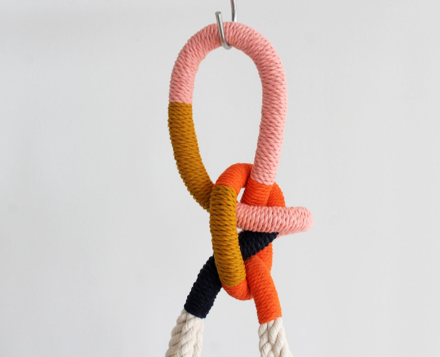 Tassel-free macrame plant hanger with mustard yellow, pink, orange, navy/indigo wrapped top loop knot holding a white ceramic bowl by Freefille
